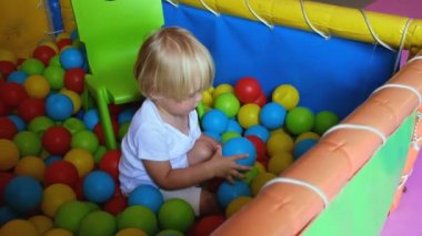 Happy playful little boy 2-3 years old in dry pool with colorful plastic balls