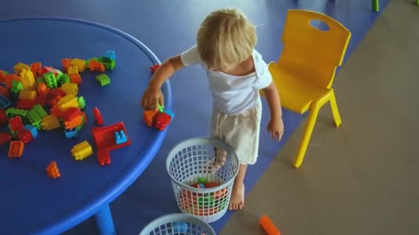 Małe dziecko wkłada kolorowego konstruktora do wiadra — Wideo stockowe
