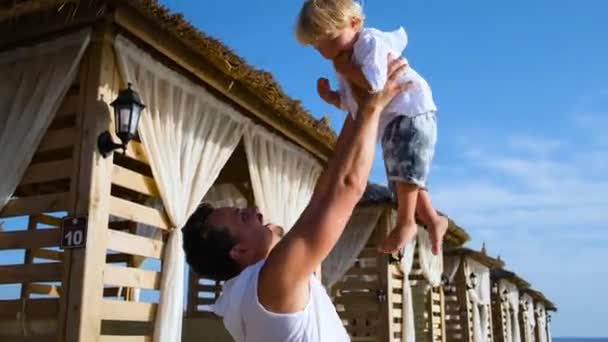 Pai joga seu filho em um resort de praia — Vídeo de Stock