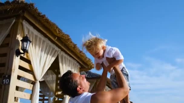 Apa feldobja a fiát egy tengerparti üdülőbe. — Stock videók