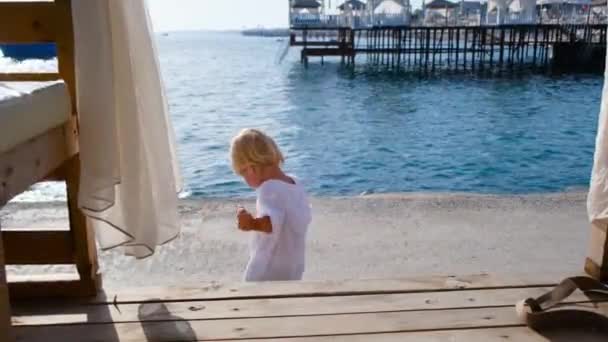 Menino em uma camisa branca junto ao mar — Vídeo de Stock