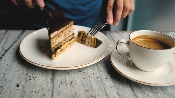 a man in a cafe drinks coffee and cuts a piece of coffee cake. High quality 4k footage