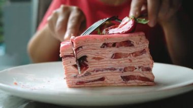 Bir kız bir parça çilekli keki bıçakla keser. Yüksek kalite 4k görüntü