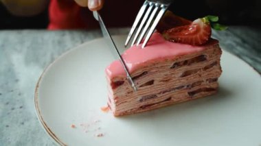 Bir kız bir parça çilekli keki bıçakla keser. Yüksek kalite 4k görüntü