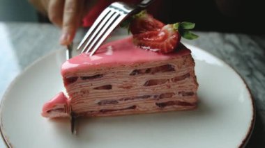 Bir kız bir parça çilekli keki bıçakla keser. Yüksek kalite 4k görüntü