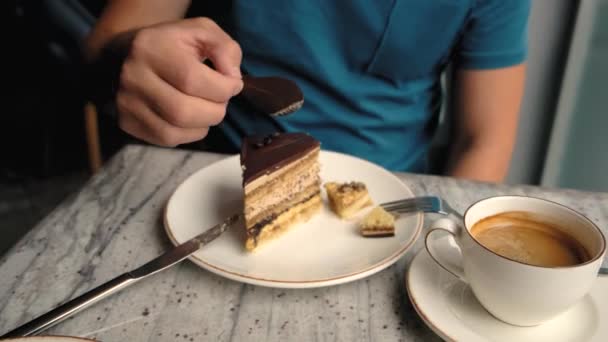 カフェの男はケーキからチョコレートの装飾を食べる 高品質4K映像 — ストック動画