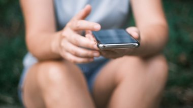 Akıllı telefon kullanan ve tutan, dokunmatik ekranda aşağı yukarı kaydıran, dışarıda oturan genç kadınların ellerini kapatın. Yüksek kalite 4k görüntü