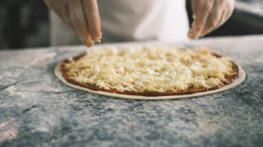 Aşçıların ellerinin pizzaya peynir koyması için kapatıyoruz. Dört Peynir. Şef pizza, üretim ve yemek dağıtımına malzemeleri ekliyor. Yüksek kalite 4k görüntü