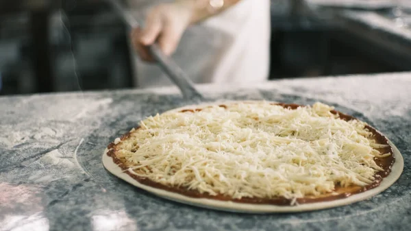 The chef puts the pizza in the oven for baking. Baking pizza in fast food restaurants. The chef in the kitchen prepares pizza in an industrial oven. High quality 4k footage
