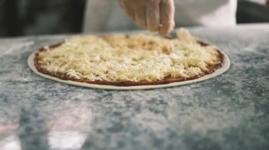 Aşçıların ellerinin pizzaya peynir koyması için kapatıyoruz. Dört Peynir. Şef pizza, üretim ve yemek dağıtımına malzemeleri ekliyor. Yüksek kalite 4k görüntü