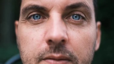 Parlak mavi gözlü, yakından bakınca merakla bakan genç bir adam. Yüksek kalite 4k görüntü