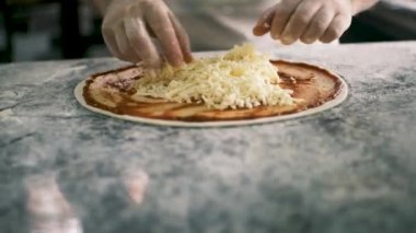 Aşçıların ellerinin pizzaya peynir koyması için kapatıyoruz. Dört Peynir. Şef pizza, üretim ve yemek dağıtımına malzemeleri ekliyor. Yüksek kalite 4k görüntü