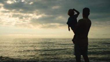 Baba ve oğul gün batımında plajda oynuyorlar. Arkadaş canlısı aile kavramı. Yüksek kalite fotoğraf