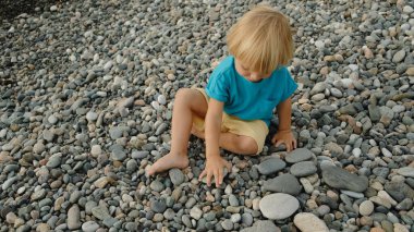 Bir çocuk sahilde taşlarla oynar. Yüksek kalite 4k görüntü