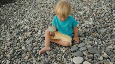 Bir çocuk sahilde taşlarla oynar. Yüksek kalite 4k görüntü