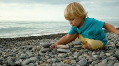 Bir çocuk sahilde taşlarla oynar. Yüksek kalite 4k görüntü