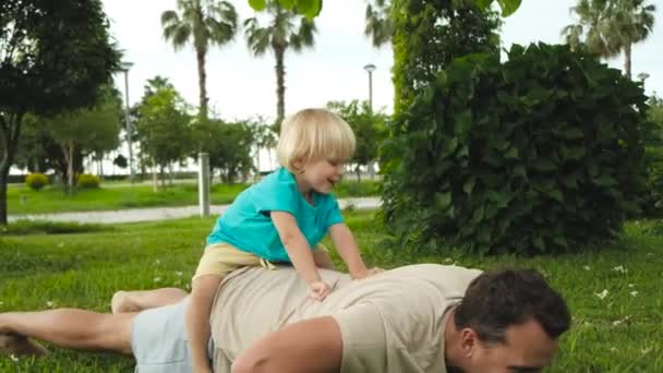Criança Sobe Nos Pais Volta Enquanto Pai Faz Flexões Chão — Vídeo de Stock