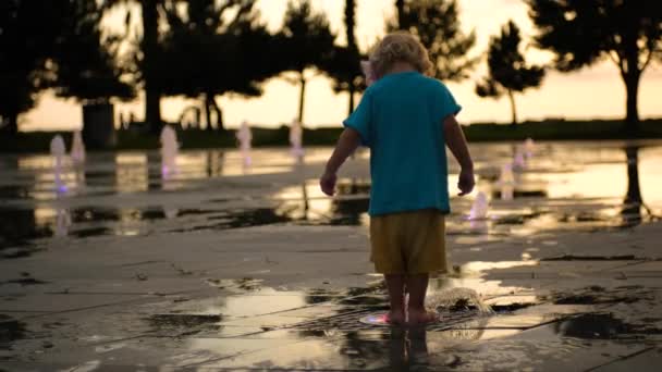日没時に噴水の水で遊んでいる小さな子供です 高品質4K映像 — ストック動画