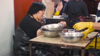 a Georgian woman smokes a cigarette and cleans the fish at the fish market without listening to the cigarette from her mouth. July 2022. Georgia-Batumi. High quality 4k footage
