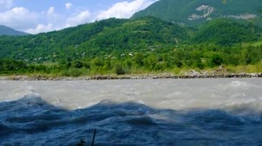 Slow motion of stormy mountain river. Beautiful mountain scenery in the background. High quality 4k footage