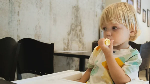 Attractive Boy Eats Banana Sits Table Restaurant Carefully Watching Cartoons — Fotografia de Stock