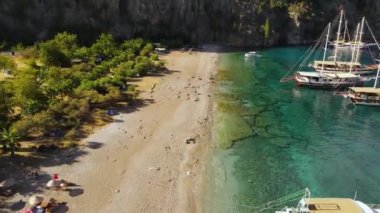 Kelebek Vadisi. Gemileri körfezde demirli mavi denizle birlikte hava aracı tam karşıdan dönüyor. Yüksek kaliteli FullHD görüntüler
