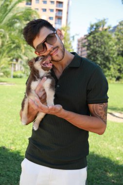 Koyu saçlı yakışıklı bir adam ve yavru köpeği, ikisi de çok mutlu.