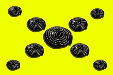 Sarı zemin üzerinde sarmal şekilli siyah meyan kökü şekeri.