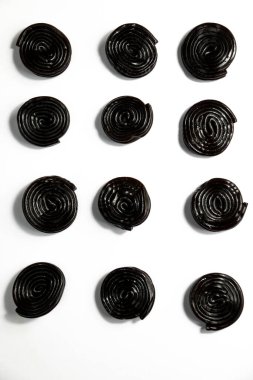 Sarı zemin üzerinde sarmal şekilli siyah meyan kökü şekeri.