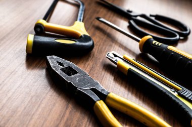 Çeşitli sarı alet seti, tornavida, pense, testere.