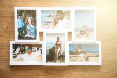 Yazın Mallorca sahillerinde birbirini seven bir çiftin birkaç fotoğrafının beyaz çerçevesi. Kahverengi ahşap bir arka planı var.