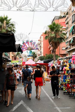 Alicante, İspanya; 21 Haziran 2022: Alicante Şenlik Yangınları, insanlar Foguera Carolinas Altas yakınlarındaki sokak pazarına bakarken sokaklarda şenliklerle yürüyorlar.