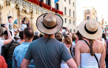 Alicante 'den turistler ve insanlar cep telefonlarıyla izleyip kayıt yapıyorlar. Arka plandaki devler Alicante şenlik ateşi şenliklerinde geçit törenleri ve danslar yapıyorlar..