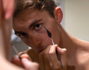 Painting a drop on his sad face. Youth mental disorder, expression and depression