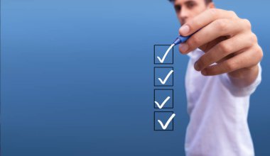 Young man checking 4 boxes with list of options on blue background