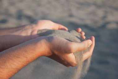Sand flowing through the fingers of a man's hand, desert sand in the dunes of Patara in Turkey