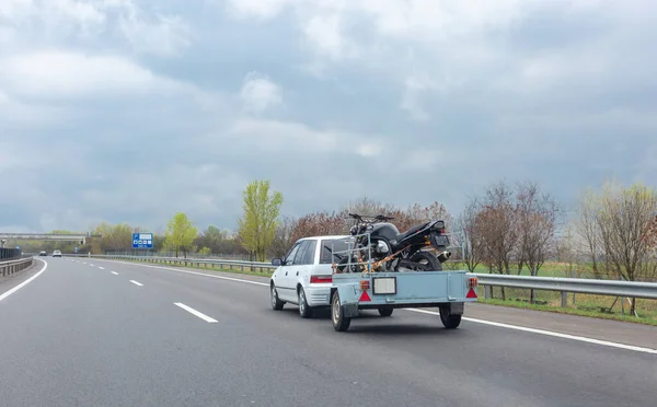 Karavanda elinde motosikletle beyaz bir araba sürüyordu.. 
