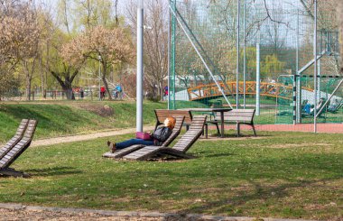 Nyiregyhaza, Macaristan 24 Mart 2019. Salt Lake Parkı. Tahta mobilyalar, futbol sahası, tahta güneş pansiyonunda dinlenen kızıl saçlı kız.