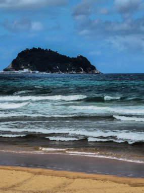 Kuzey İspanya 'da Zarautz plajında vahşi deniz manzaralı Getaria fare şekilli ada manzarası.