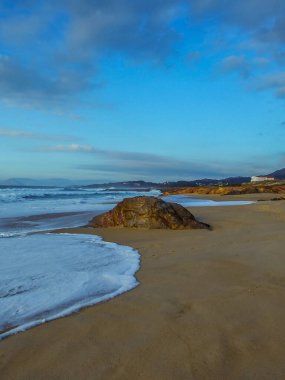 Güneşli bir günde deniz tarafından yıkanan ıssız bir kaya.