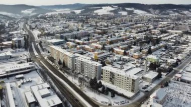 Aerial drone footage flying overlooking housing estates, public parks and commercial properties in a built up area in the small town of Bardejov in Slovakia during winter snowy sunrise, river Topla