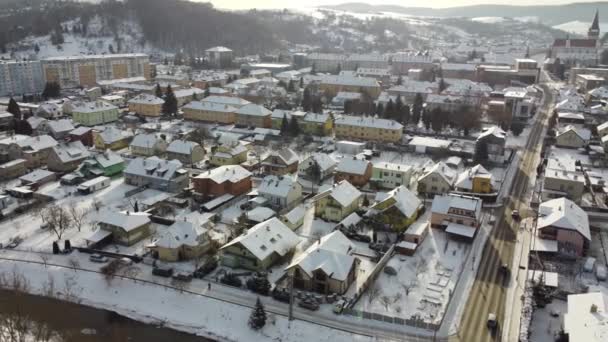 Aerial drone footage flying overlooking housing estates, public parks and commercial properties in a built up area in the small town of Bardejov in Slovakia during winter snowy sunrise, river Topla — Wideo stockowe