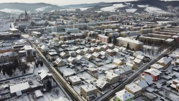 Aerial drone footage flying overlooking housing estates, public parks and commercial properties in a built up area in the small town of Bardejov in Slovakia during winter snowy sunrise, river Topla — стоковое видео