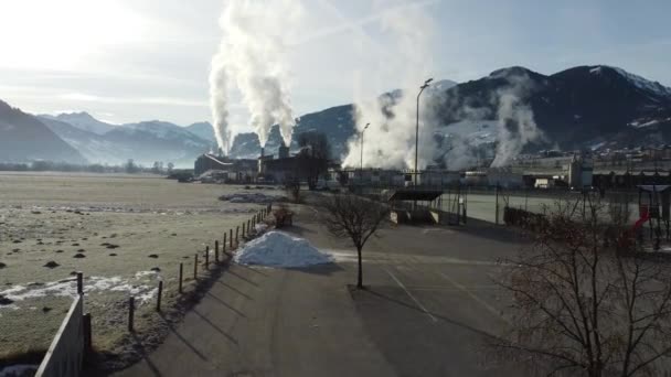 Wood sawmill proccessing wood logs and manufacturing wooden cuts and chimneys smoke is polluting the environment in beautiful natural set of deep valley surrounded by mountains — Vídeos de Stock