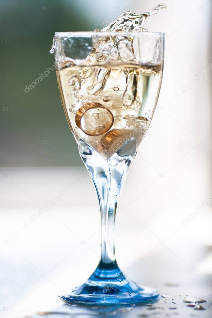 close up of wedding rings falling into a glass of champagne
