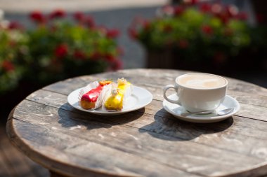 a mug of coffee on table and a delicious eclair on a plate