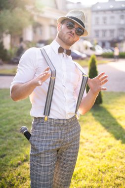 Yakışıklı sunucu ve şovmen şık bir takım elbise ve şapkayla en iyi duygular ve akrobatik hilelerle poz veriyor.