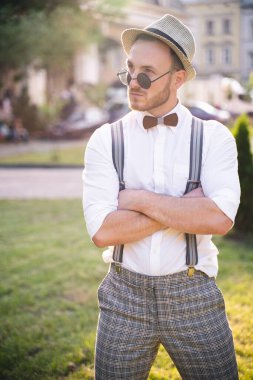 Yakışıklı sunucu ve şovmen şık bir takım elbise ve şapkayla en iyi duygular ve akrobatik hilelerle poz veriyor.