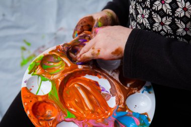 Yeni yürümeye başlayan çocuk parmaklarını boyayıp renkleri itiyor.