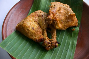 Izgara tavuk ya da ayam bakar ya da ayam panggang muz yaprağı ile servis edilir, toprak tabaklarında soğan, beyaz arka planda izole.